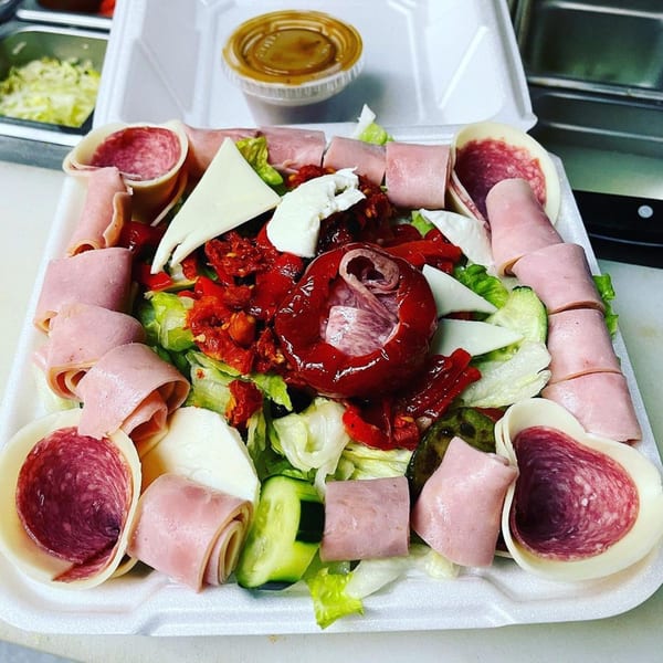 Al's Famous Pizza Italian antipasto salad with meats, cheeses, and vegetables in a takeout container.